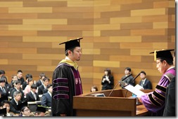 楠見学長から学位記を授与される商学研究科総代の柴﨑 英さん(矢田ゼミ）