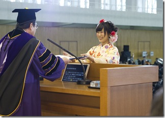  楠見学長から卒業証書を授与される商学部総代の石井さち乃さん（矢田ゼミ）