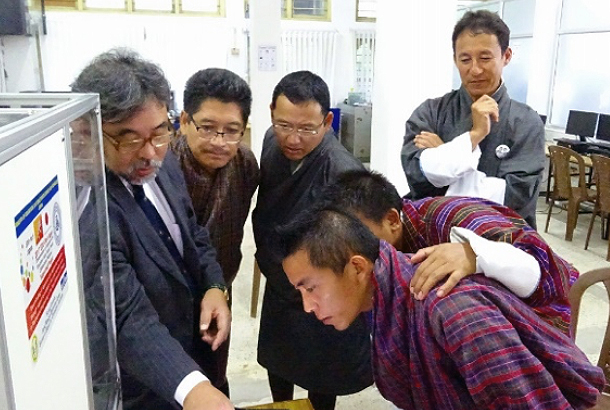 Junichi Kurata (far left) describing the components of the 3D printer to JNEC students and teachers.